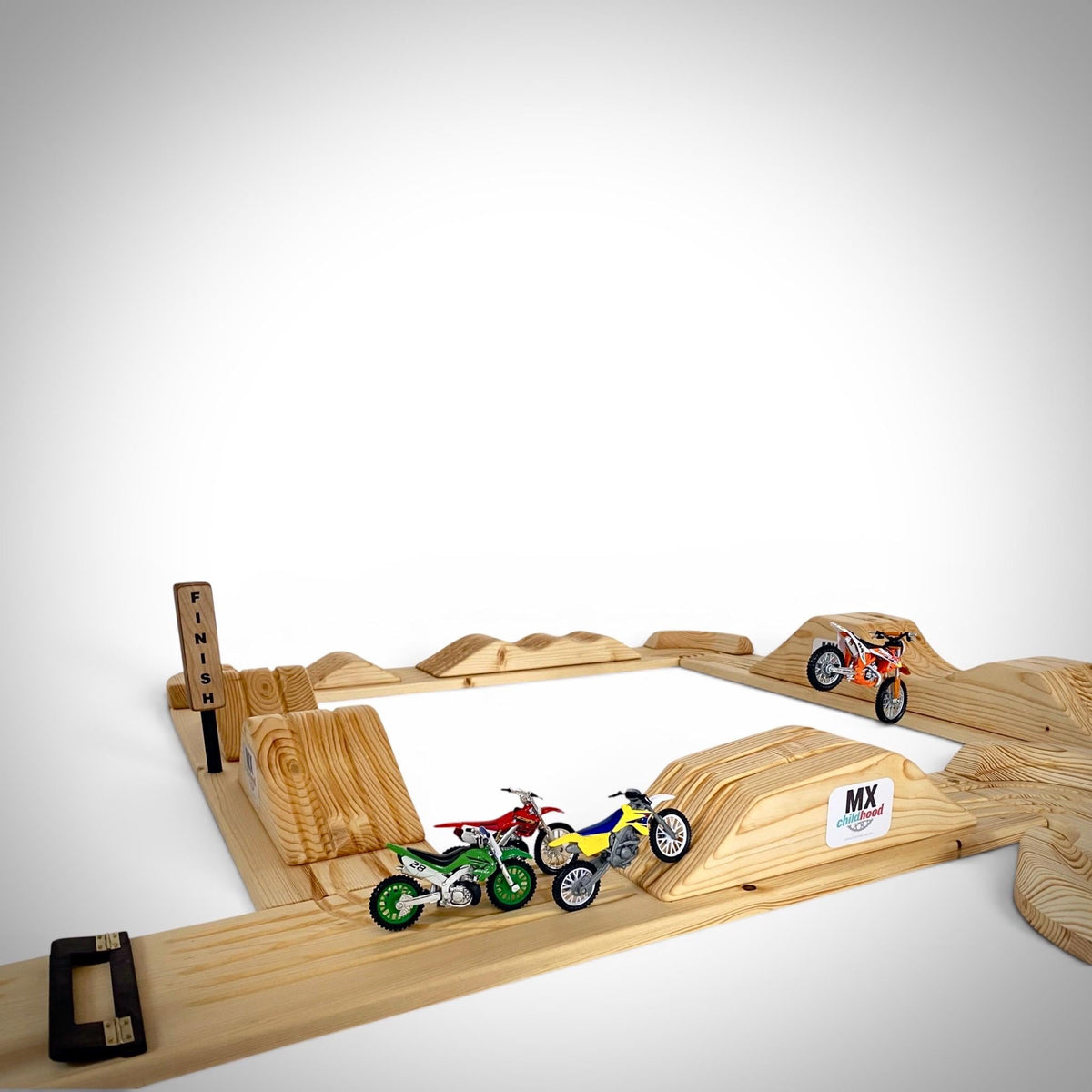 Kid playing with miniature motocross bikes on a handcrafted wooden motocross track.
