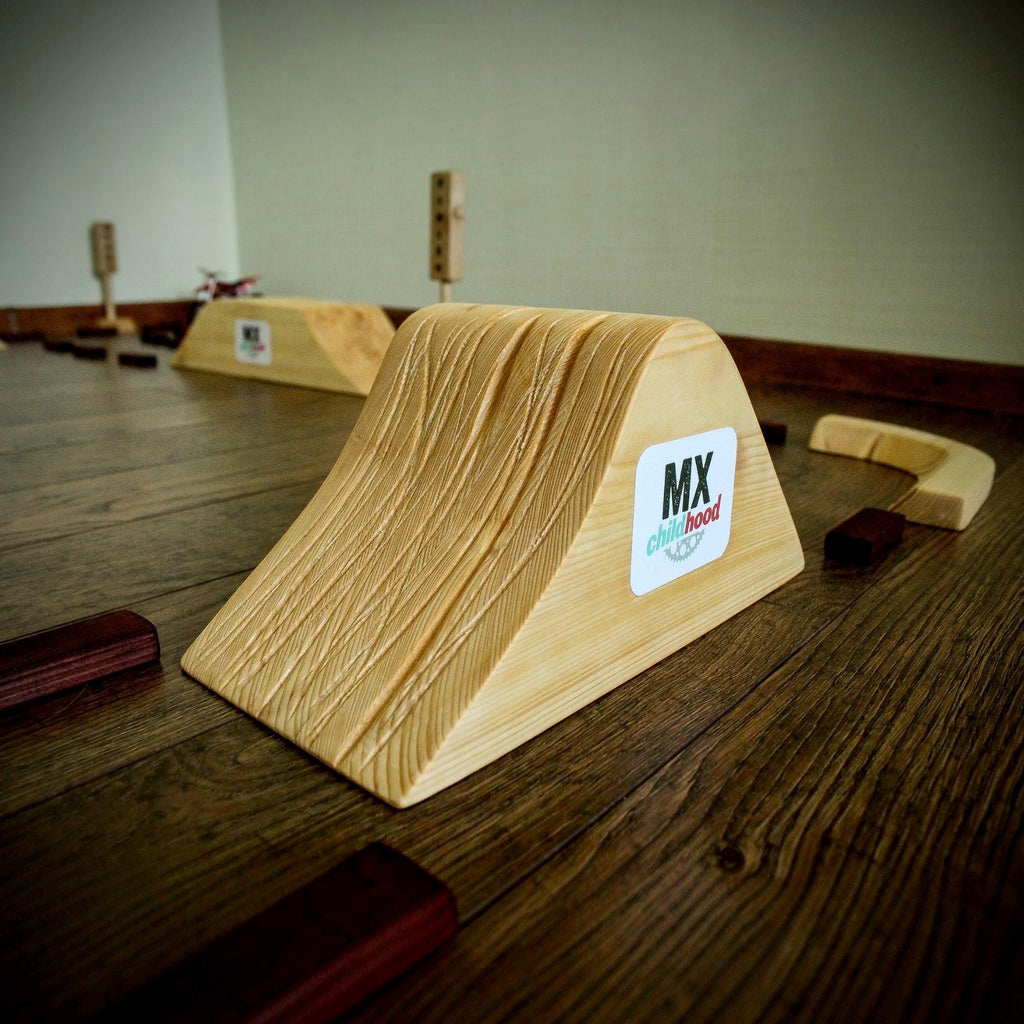 Handmade wooden dirt bike track with detailed motocross jumps and ramps, a creative racing toy for young motocross fans.