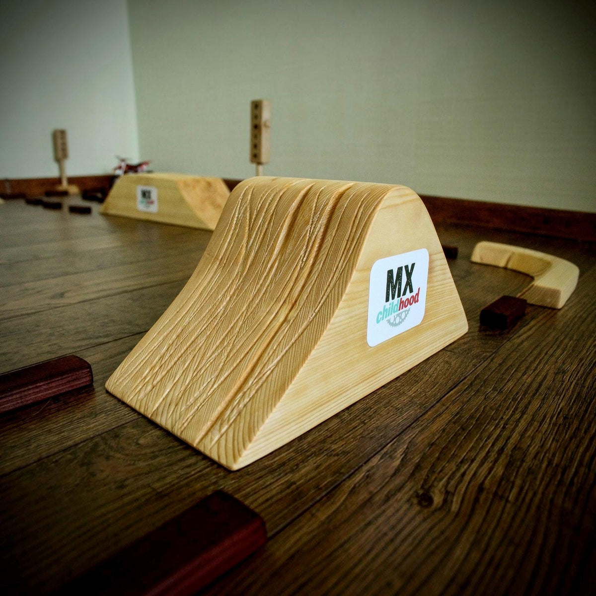 Handmade wooden dirt bike track with detailed motocross jumps and ramps, a creative racing toy for young motocross fans.